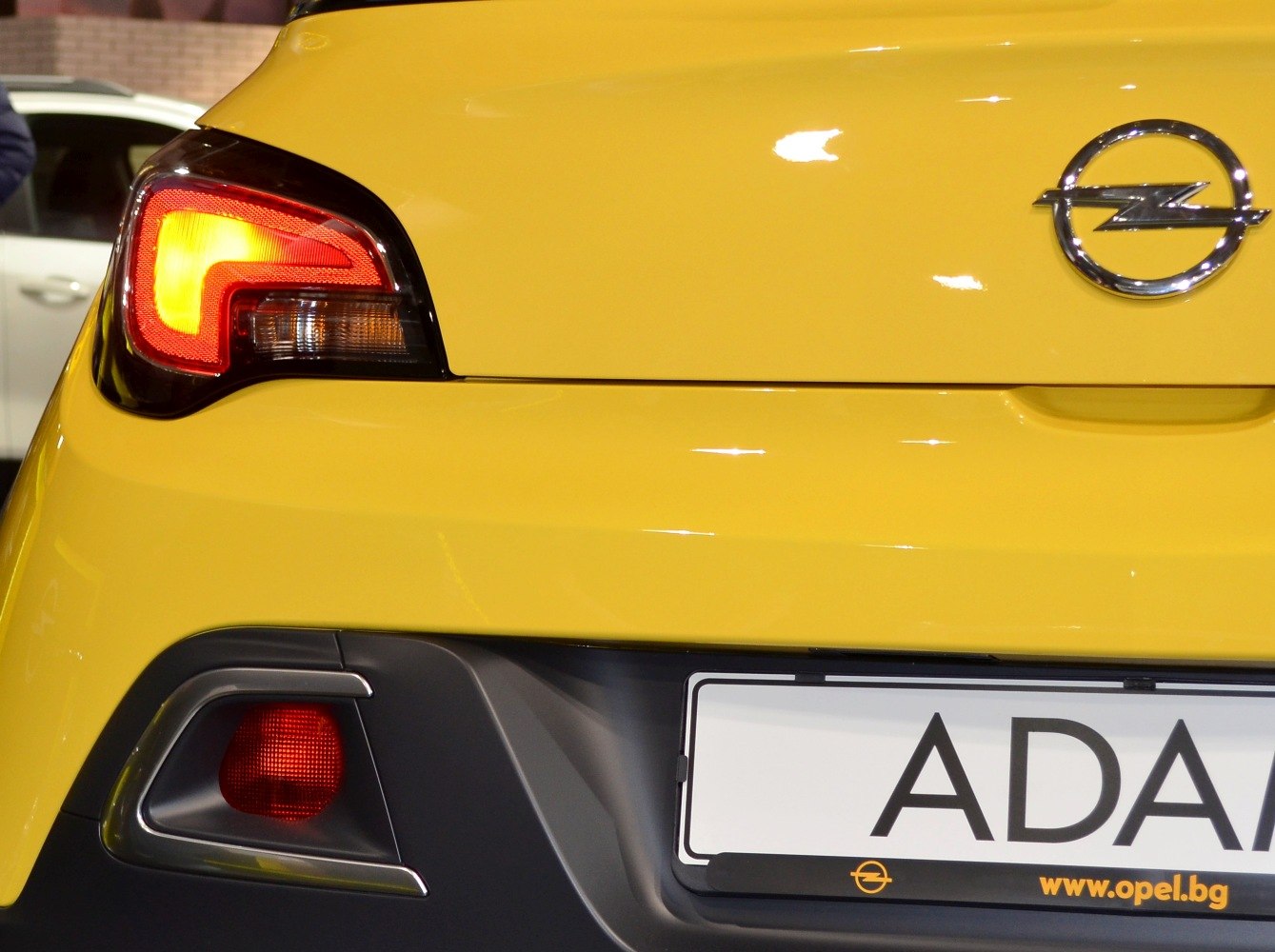 Close-up of rear tail lights and Opel emblem on yellow hatchback