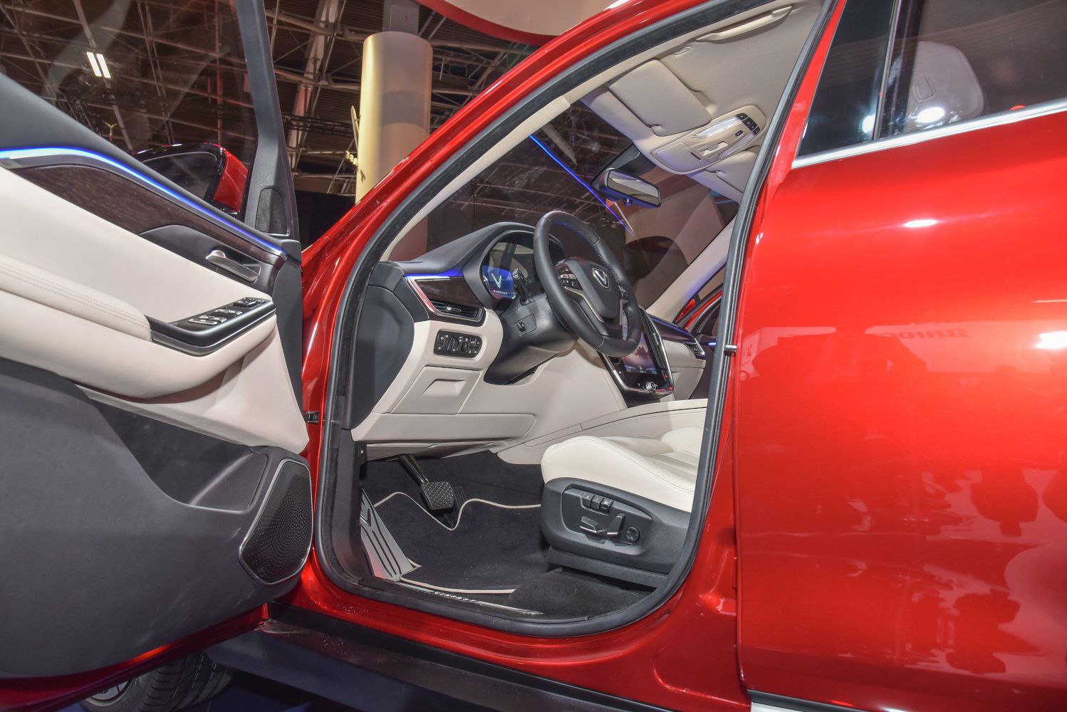 Ambient blue lighting with touchscreen and beige leather seats.