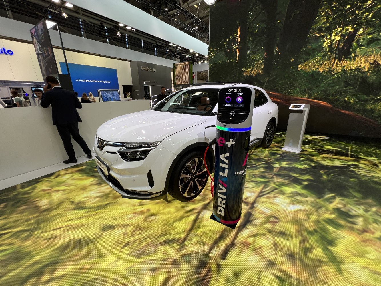 White electric SUV connected to a sleek Enel X charging station indoors