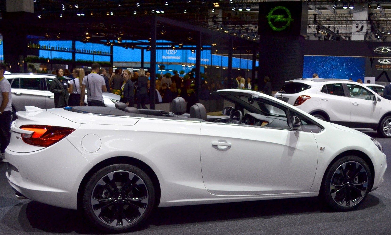 White convertible with open-top and black rims, showcasing side profile and interior seats.