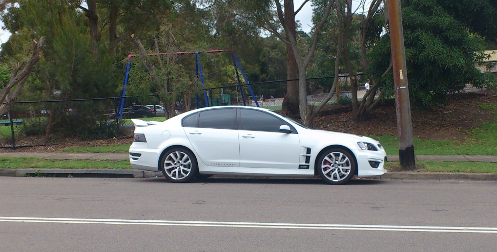 White sedan with rear spoiler and alloy wheels, side profile view