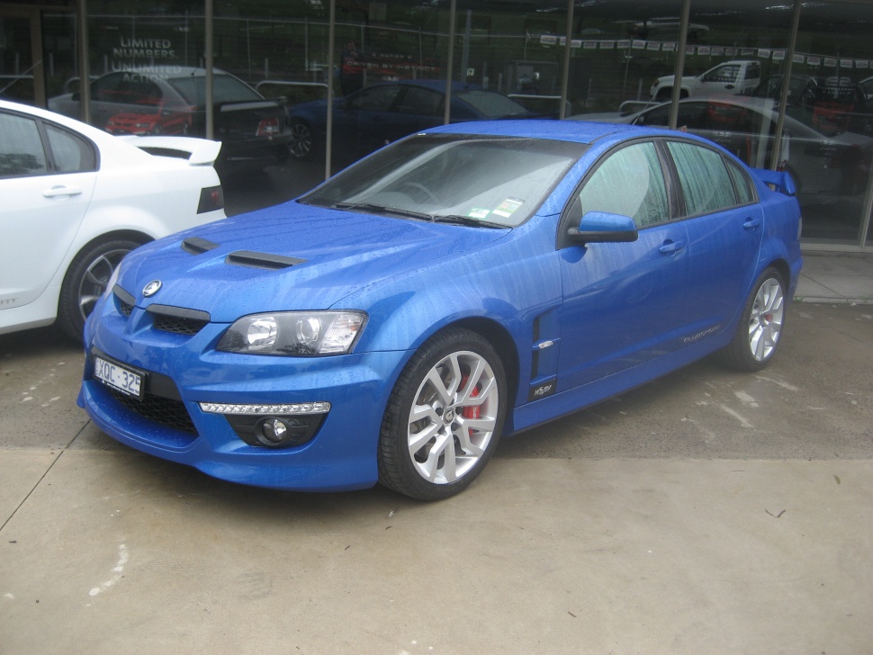 Blue performance sedan with hood vents and aggressive front styling