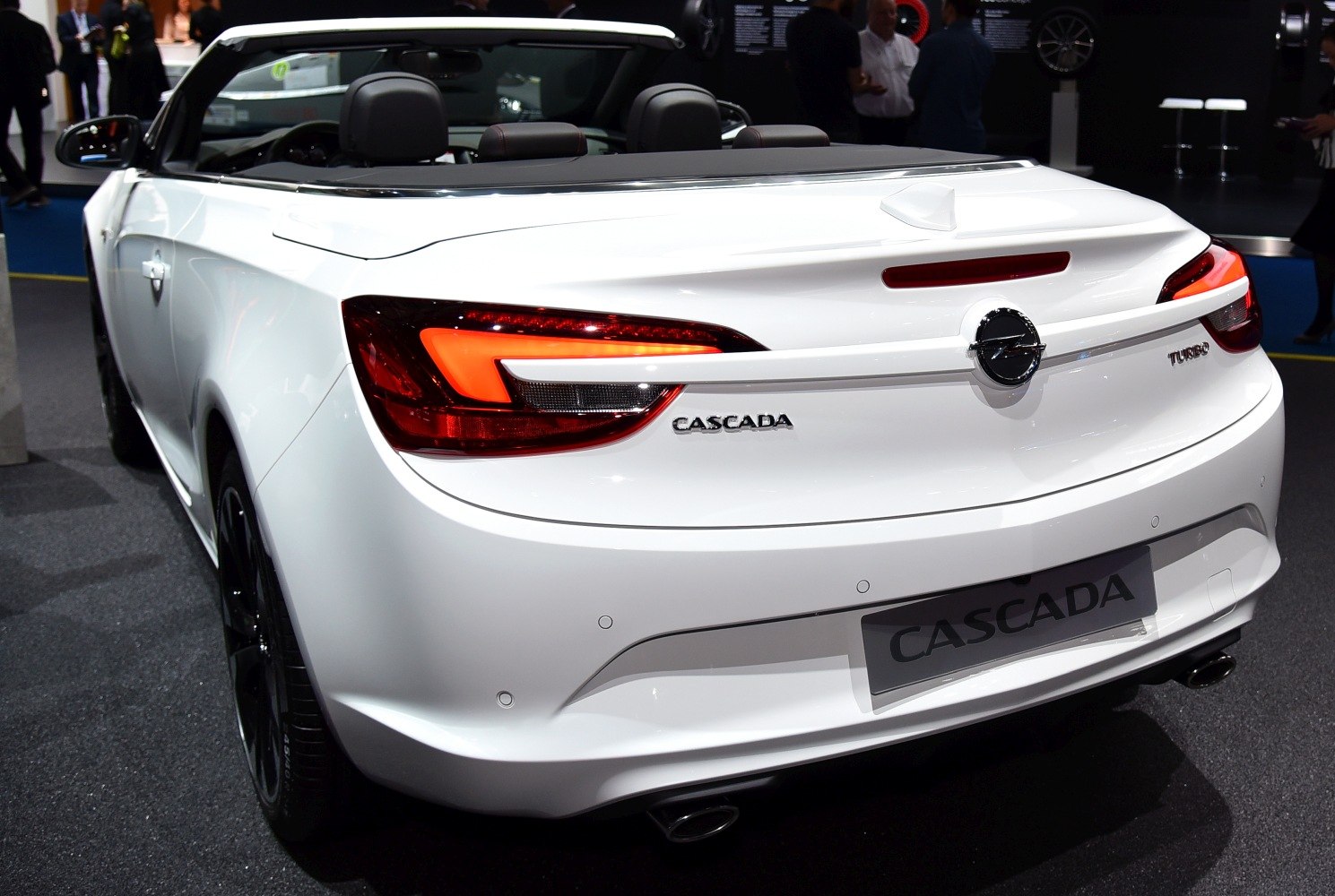 Rear view of a white convertible with distinct tail lights and open roof.