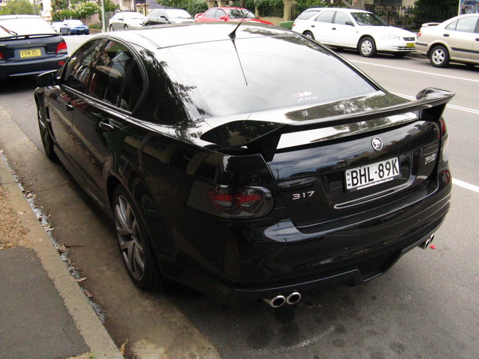 Rear view of black performance sedan with spoiler and dual exhaust