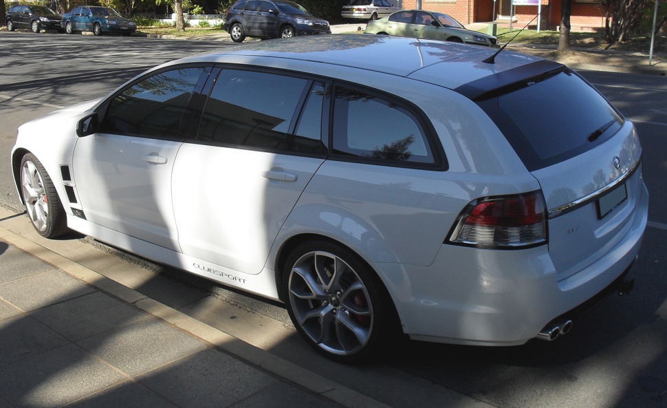 White station wagon with tinted windows and sporty wheels from rear side view