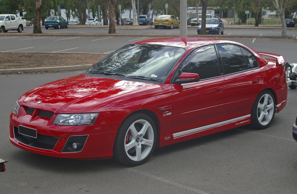 Red sports sedan with aggressive front grille and alloy wheels.