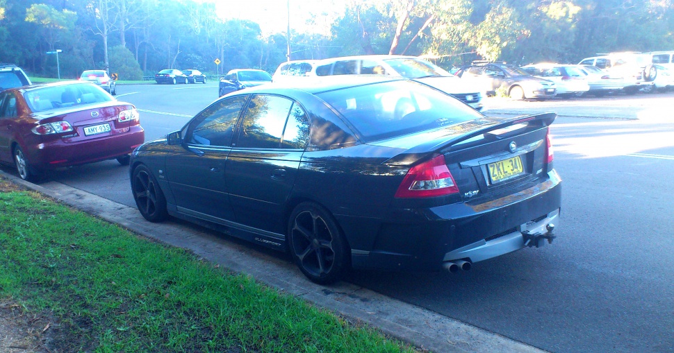 Black sedan with rear spoiler, dual exhaust, and tinted windows.