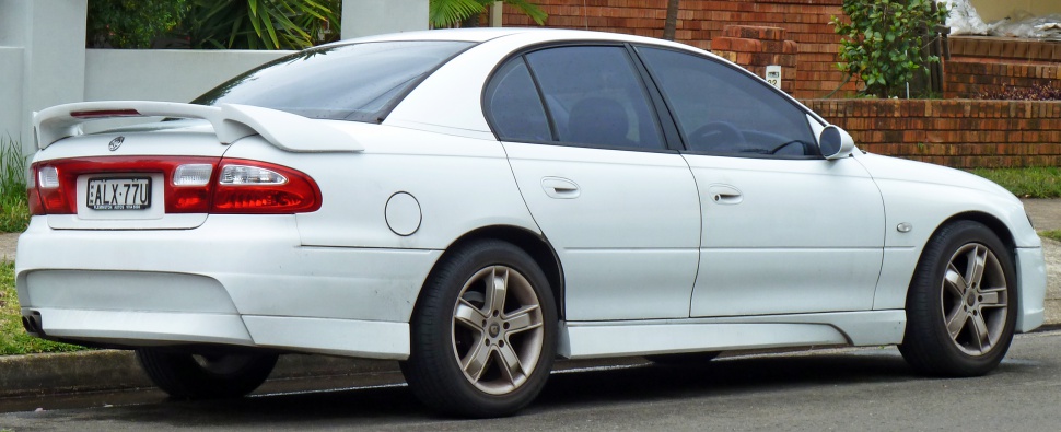 Rear side view of white sedan with spoiler and alloy wheels