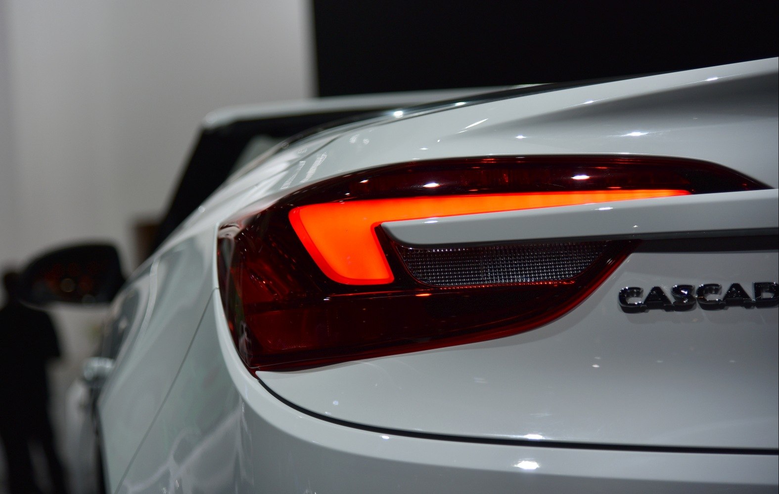 Close-up of a car's illuminated LED rear tail light with partial badge visible