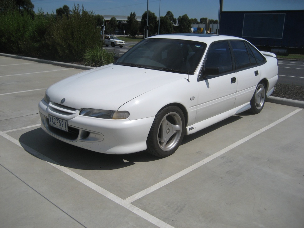 Front-side view of a white sedan with aerodynamic styling and distinctive alloy wheels