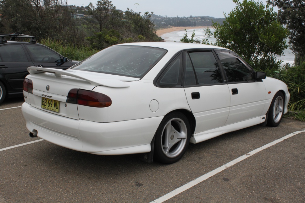 White sedan rear view with spoiler and alloy wheels