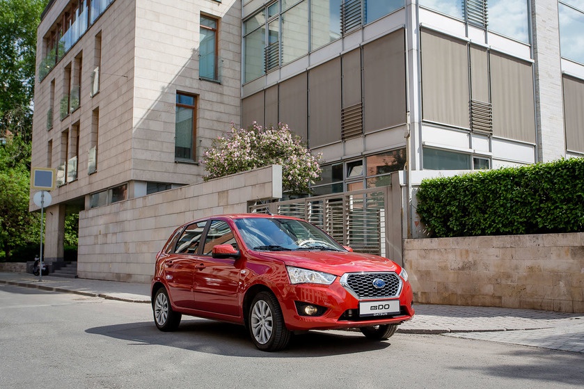 Red compact hatchback with modern grille and sleek headlights on city street