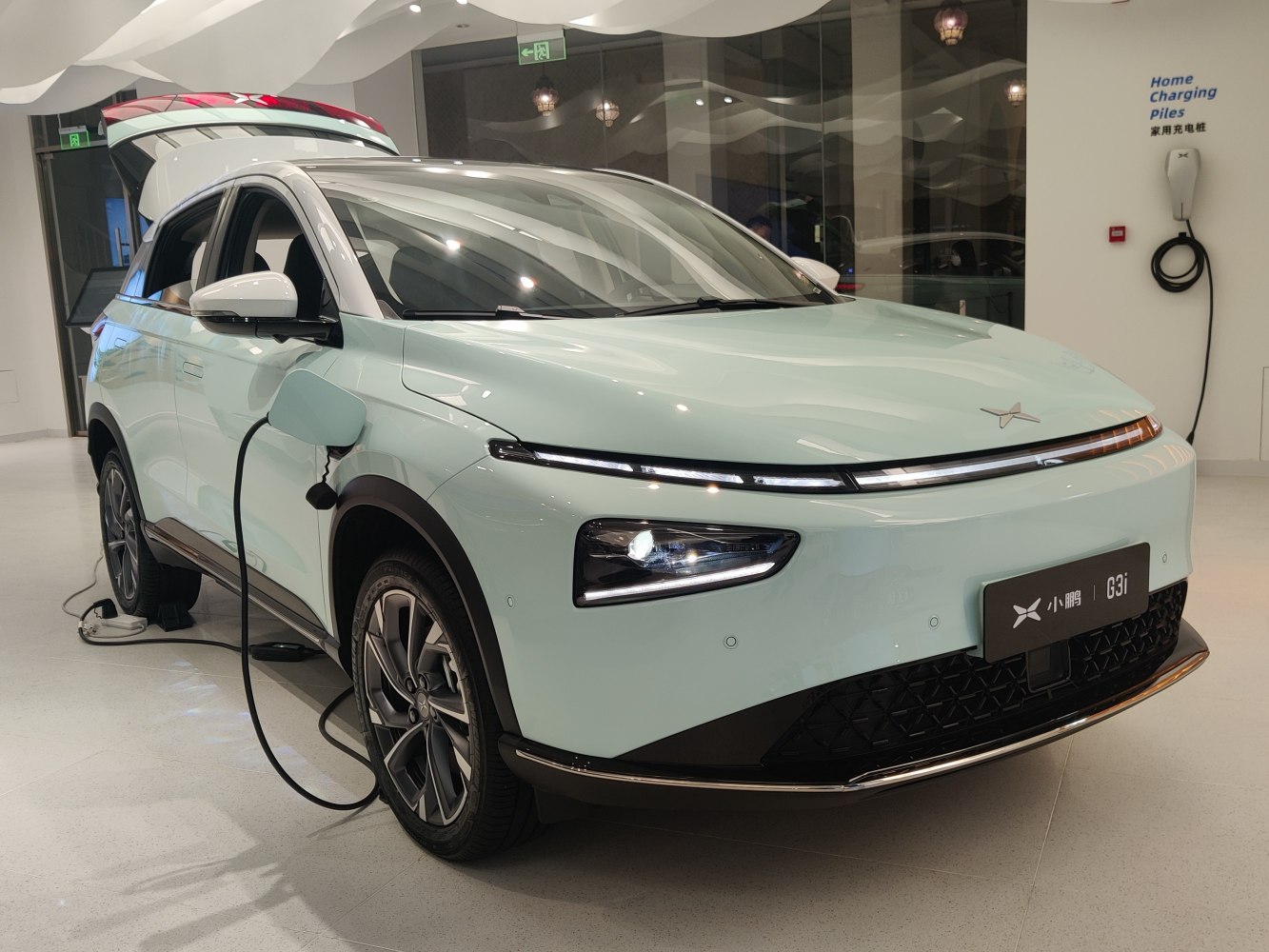 Electric SUV charging indoors with front LED lights and alloy wheels