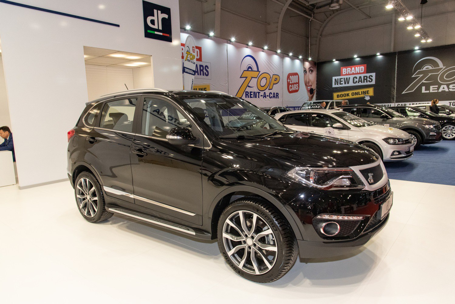 Front side view of sleek black SUV with alloy wheels at showroom
