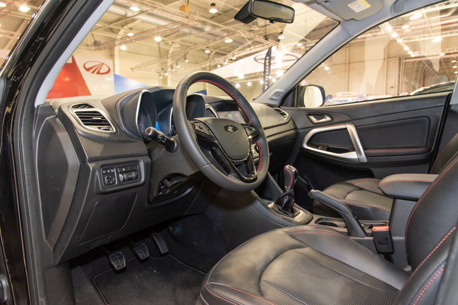 Steering wheel, manual gear shift, leather seats with red stitching inside car cabin
