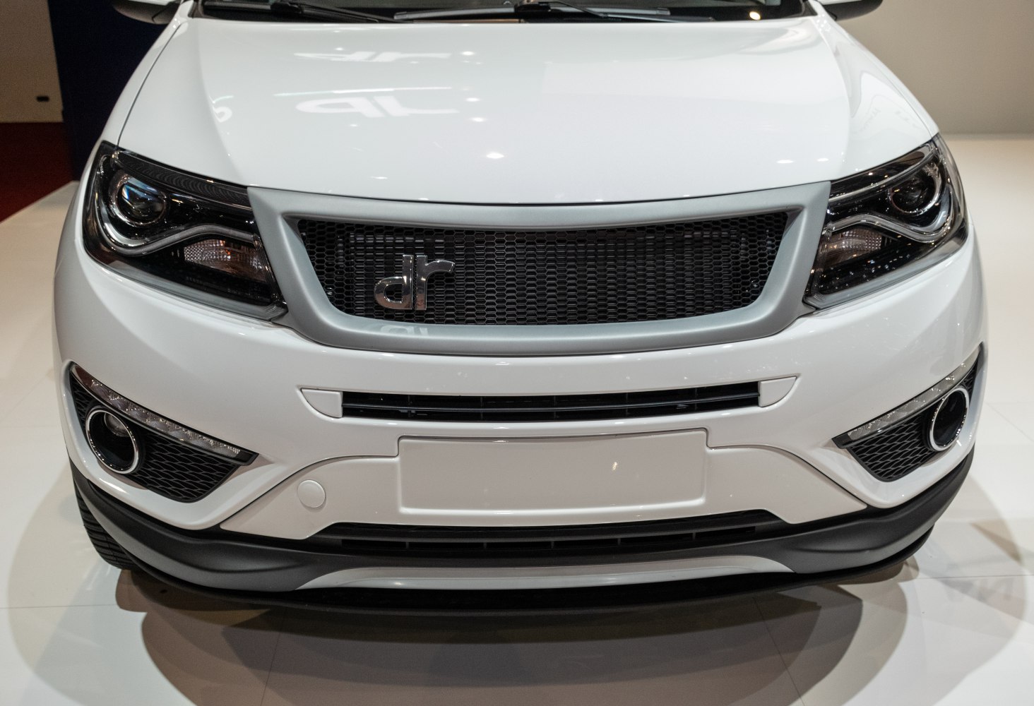 Close-up of front grille, headlights, and fog lights on white vehicle