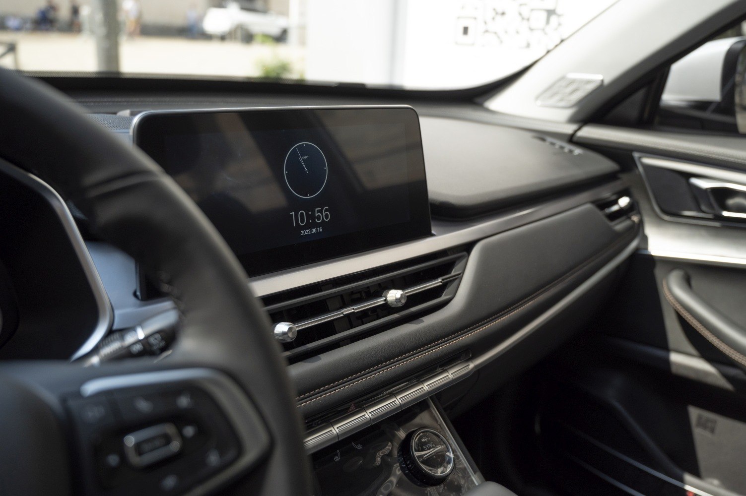 Digital clock display, air vents, and climate control knobs on car dashboard.