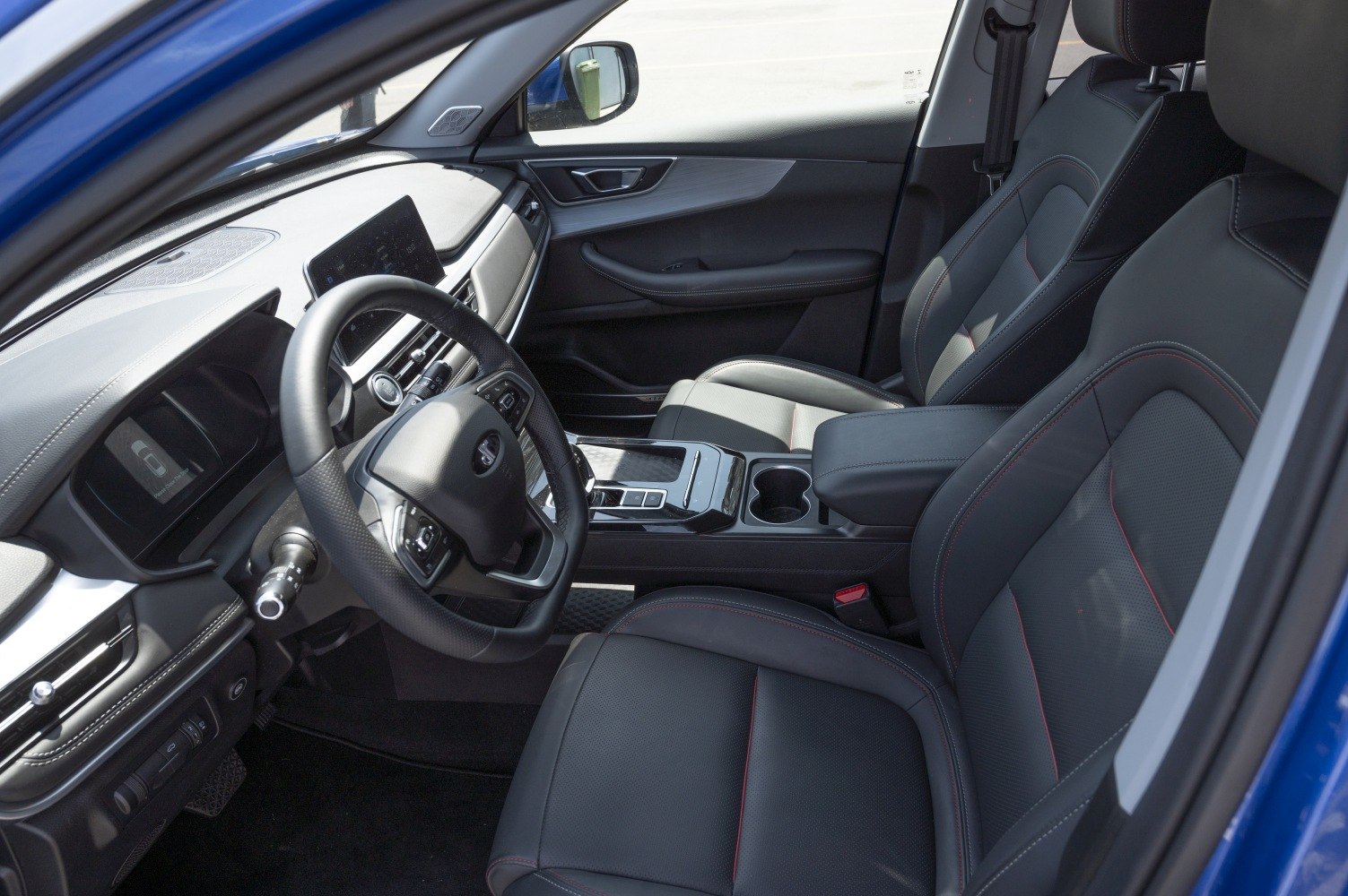 Steering wheel and dashboard with digital displays and leather seats.