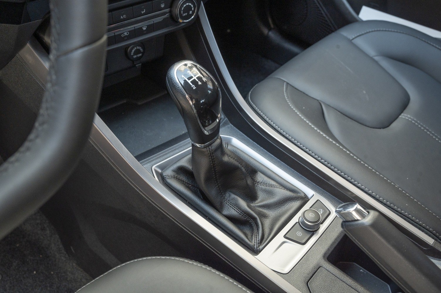 Manual transmission gear stick and leather seat with detailed stitching