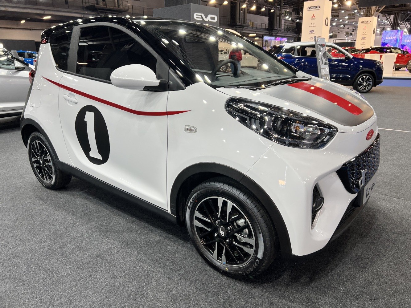 White compact electric mini vehicle with sporty racing stripes and black roof.