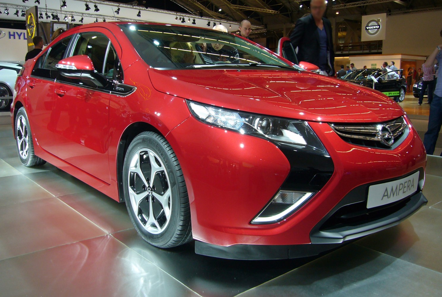 Red compact car front-side angle with alloy wheels and modern headlights