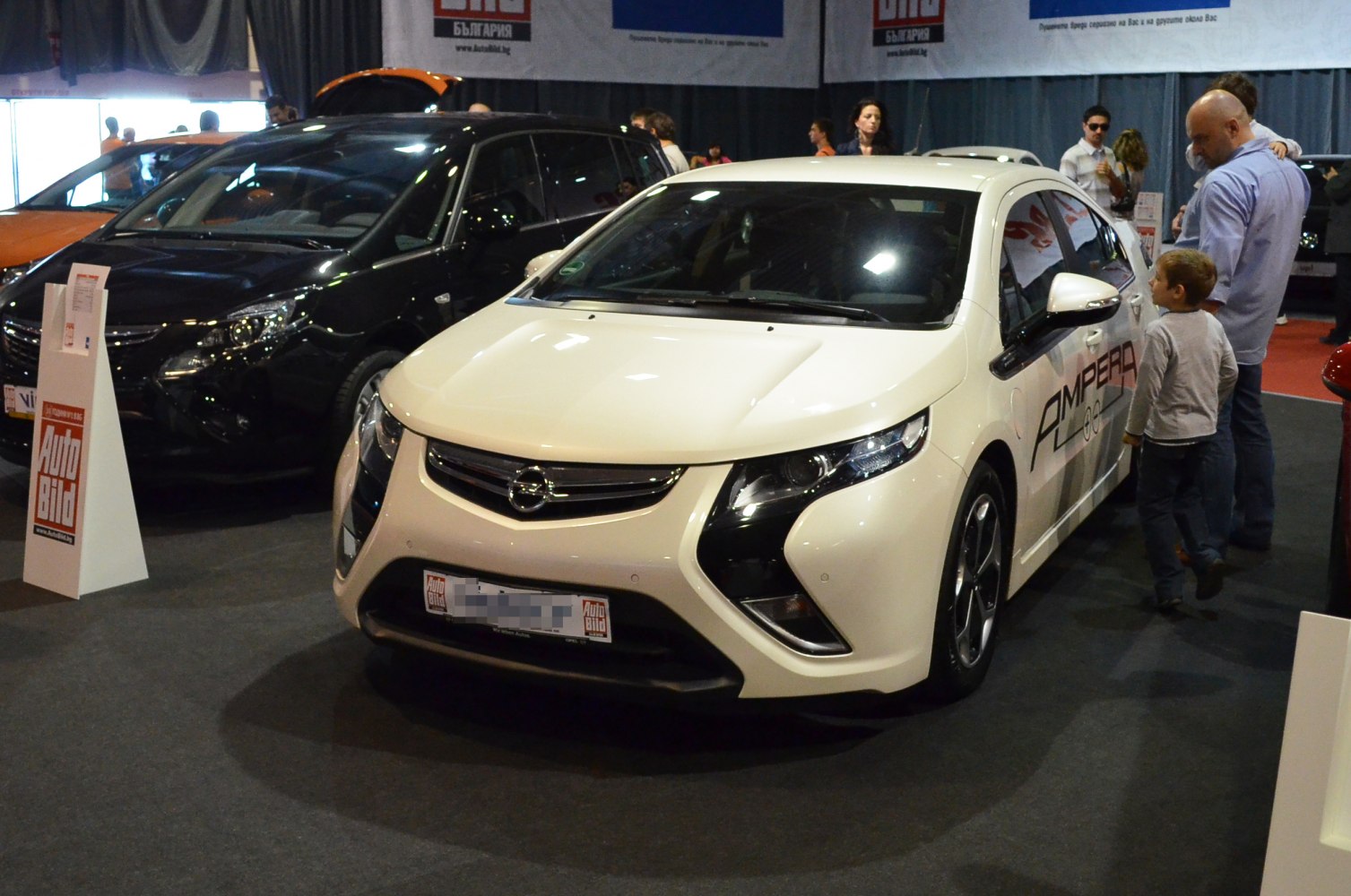 Electric hybrid car front view with distinctive headlights and sleek white body.