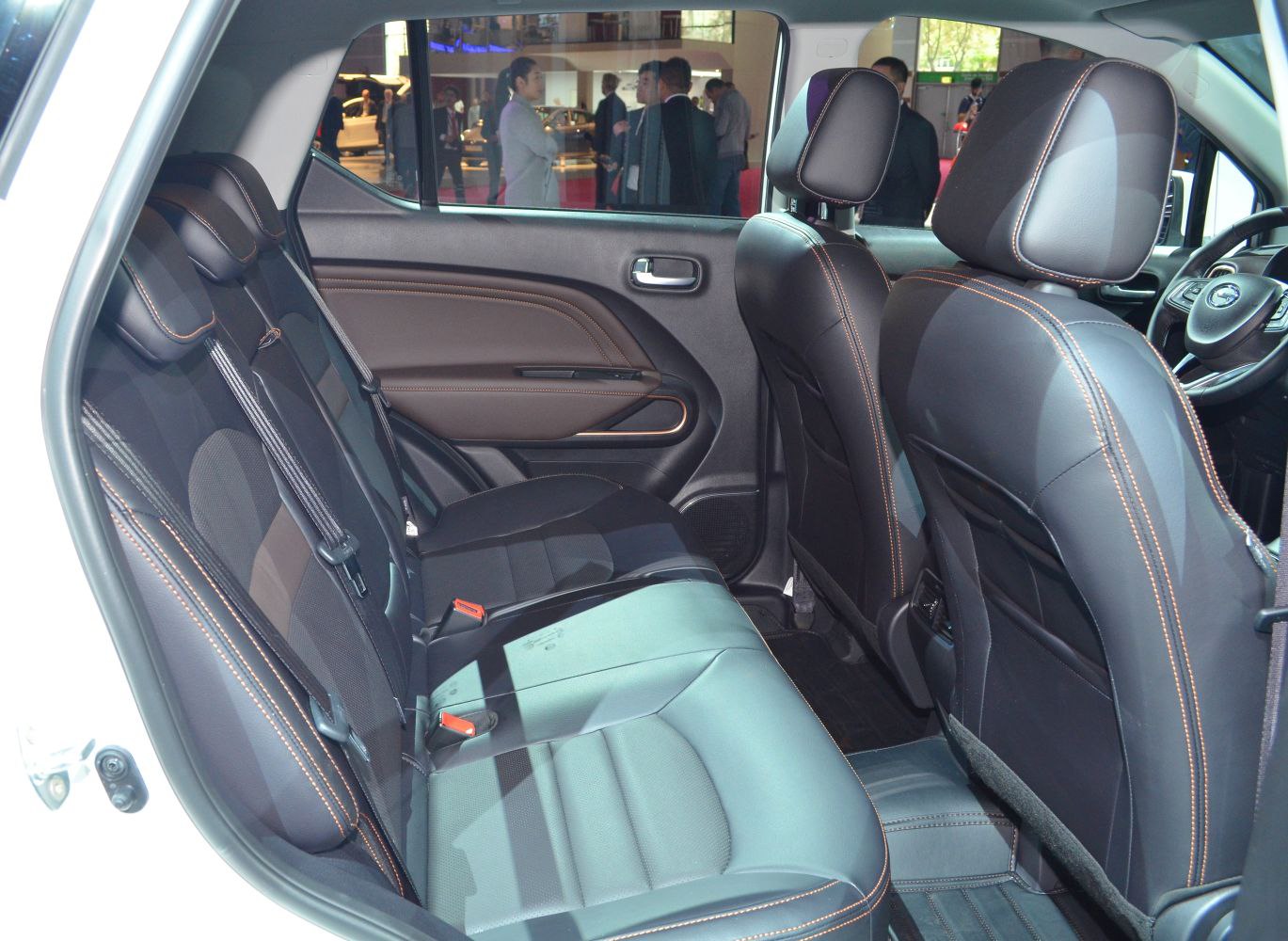 Rear interior view of black leather seats with orange stitching