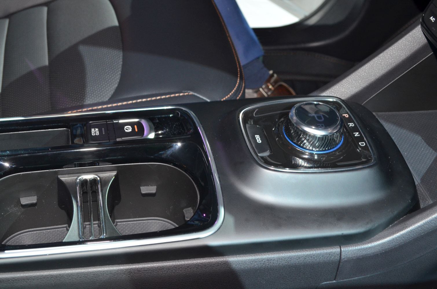 Rotary gear selector dial with electronic parking brake and cupholders.