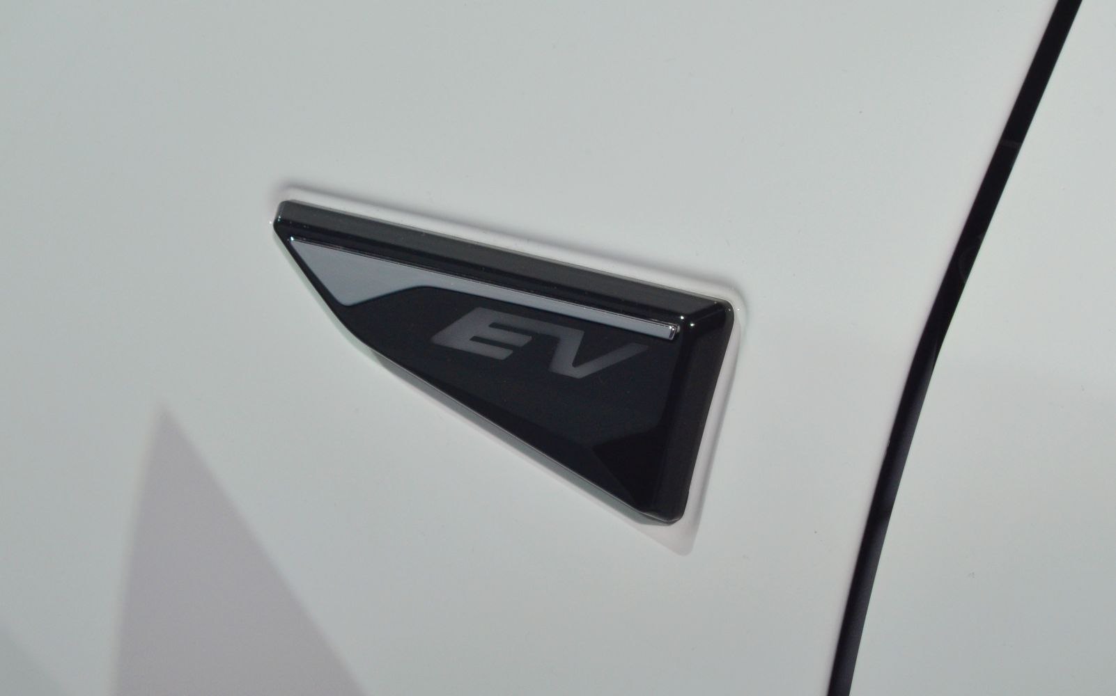 Close-up of electric vehicle EV badge on white surface