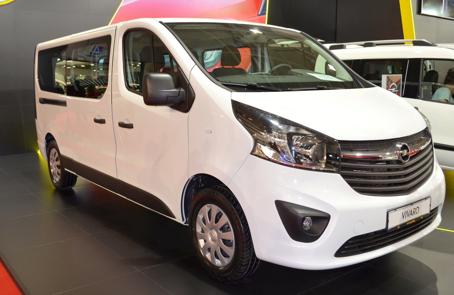 White passenger van front and side profile with large windows and modern headlights