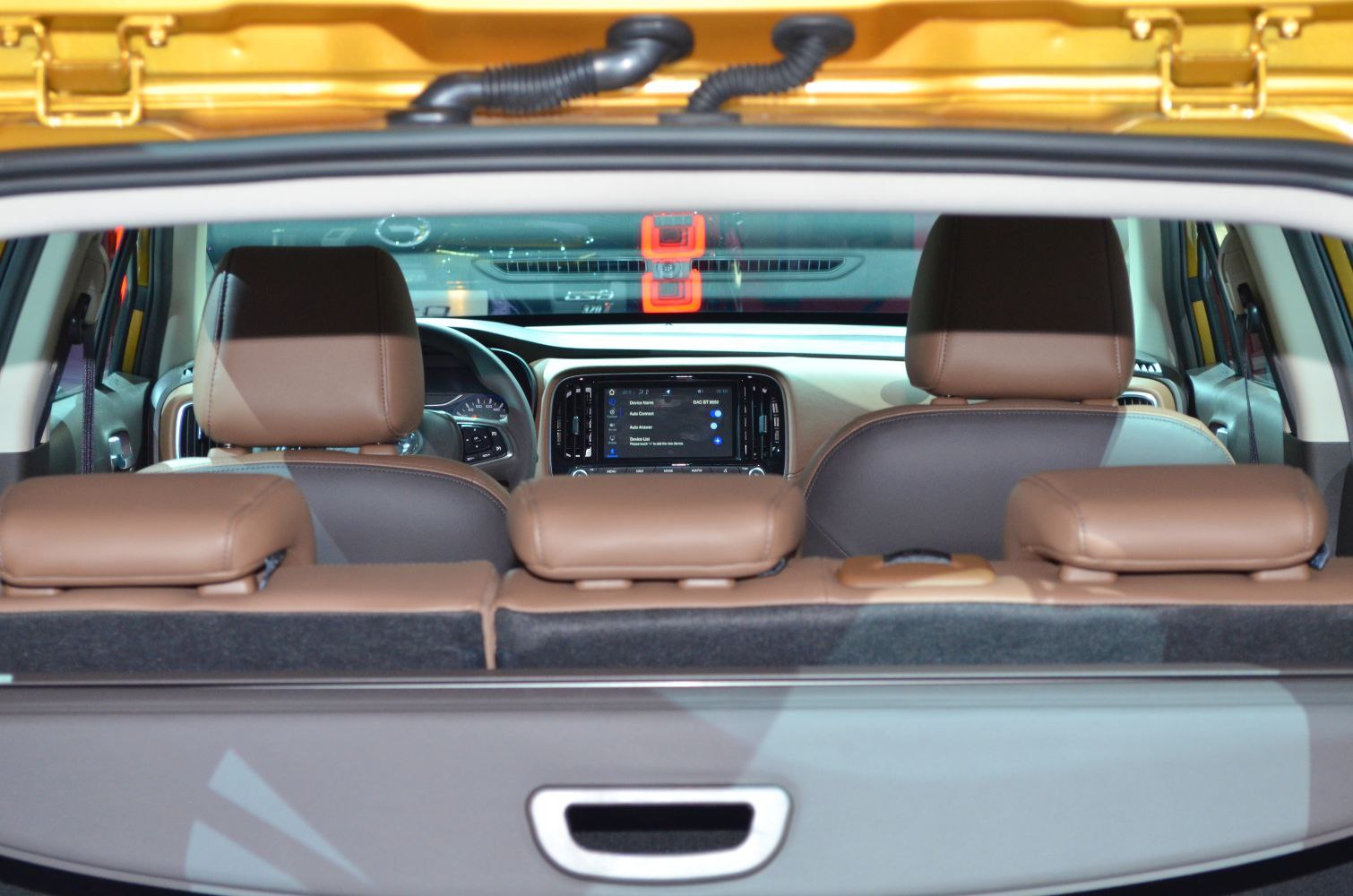 Rear view of brown seats and infotainment screen inside vehicle