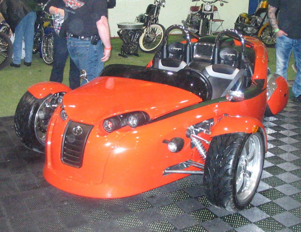 Open two-seater trike with exposed front suspension and aerodynamic body.