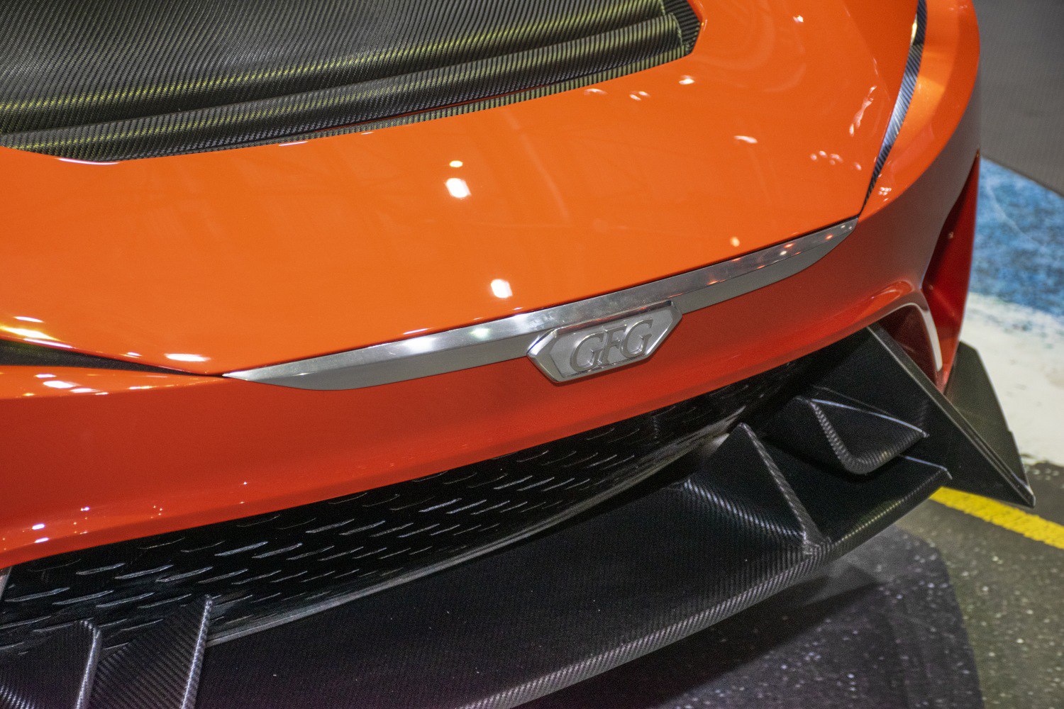 Close-up of car front with carbon fiber diffuser and sleek orange hood