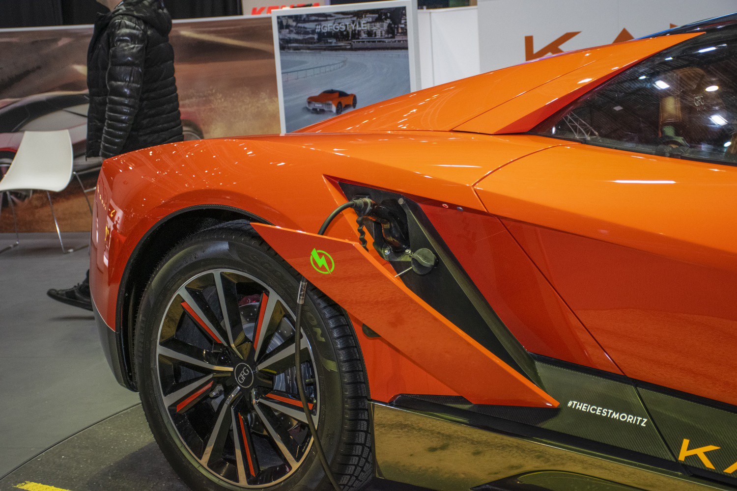 Electric charging port open with detailed rear wheel design on orange vehicle
