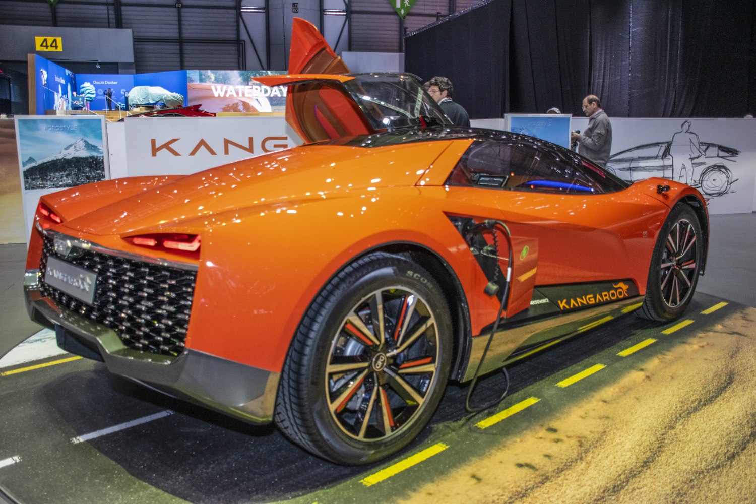 Electric coupe with gullwing door open and charging cable plugged in