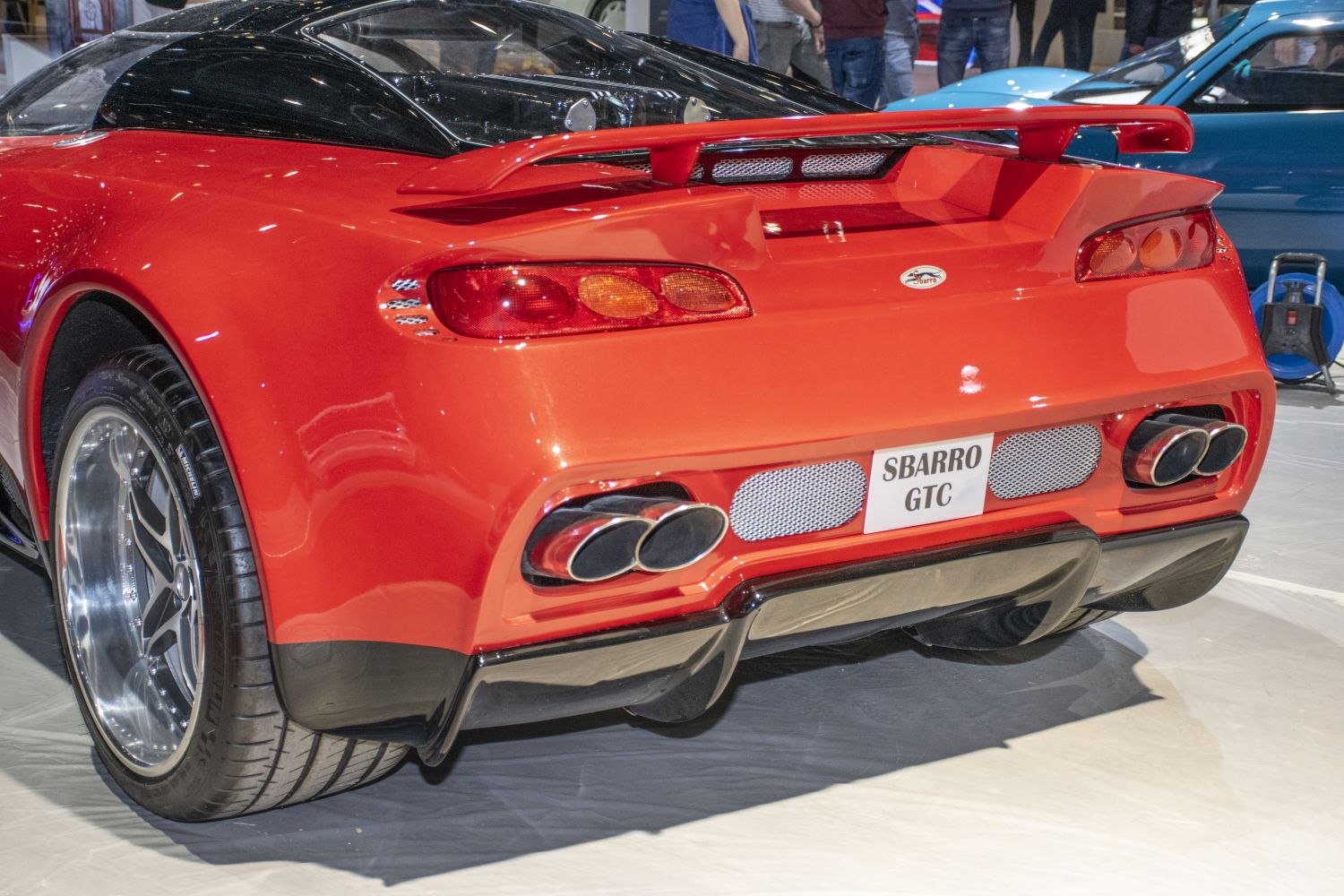 Red sports car rear with quad exhaust and distinctive tail lights.