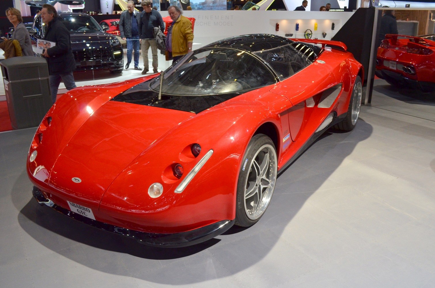 Aerodynamic red sports coupe with triple front headlights and performance wheels.