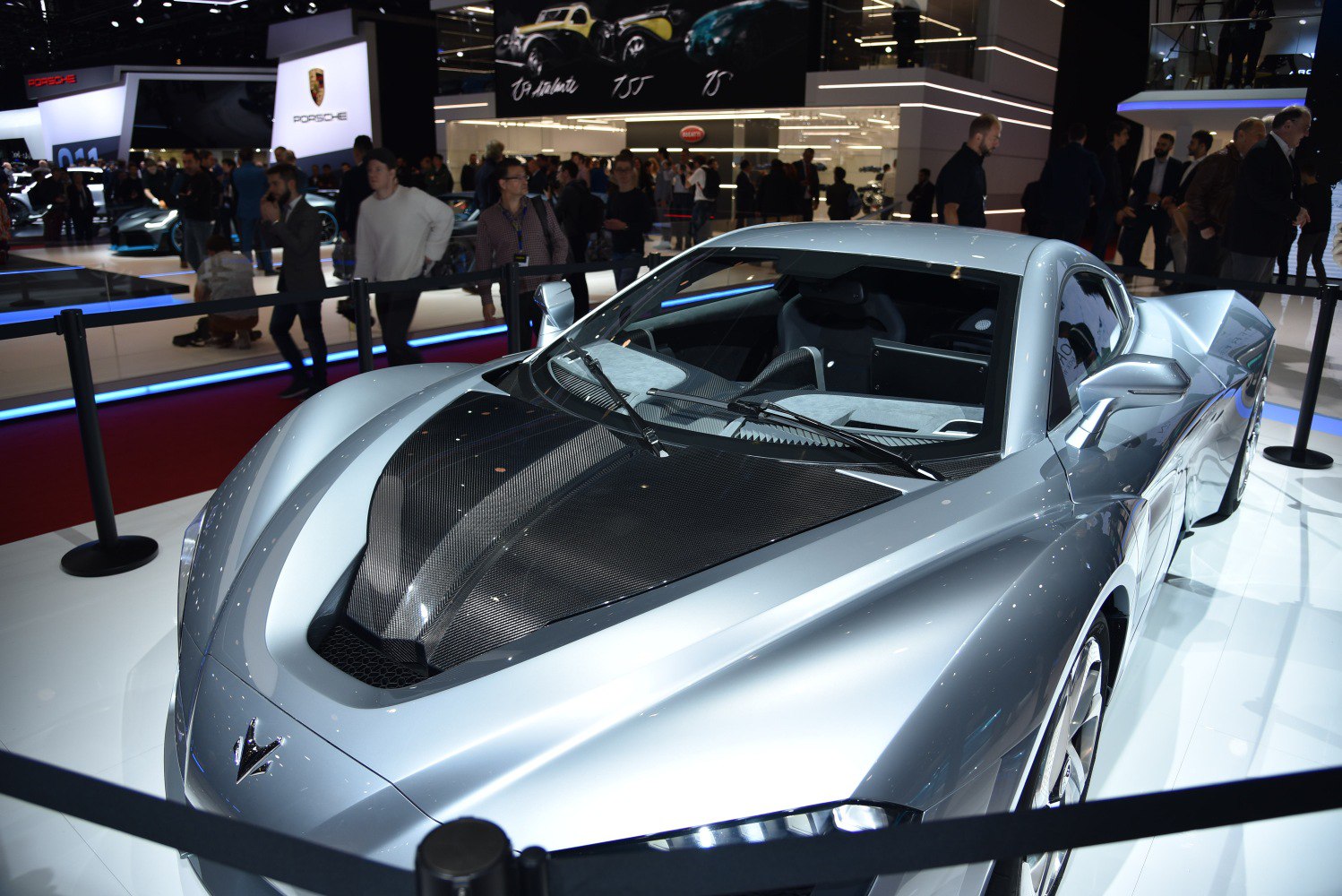 Sleek silver sports car with carbon fiber hood and aerodynamic features.