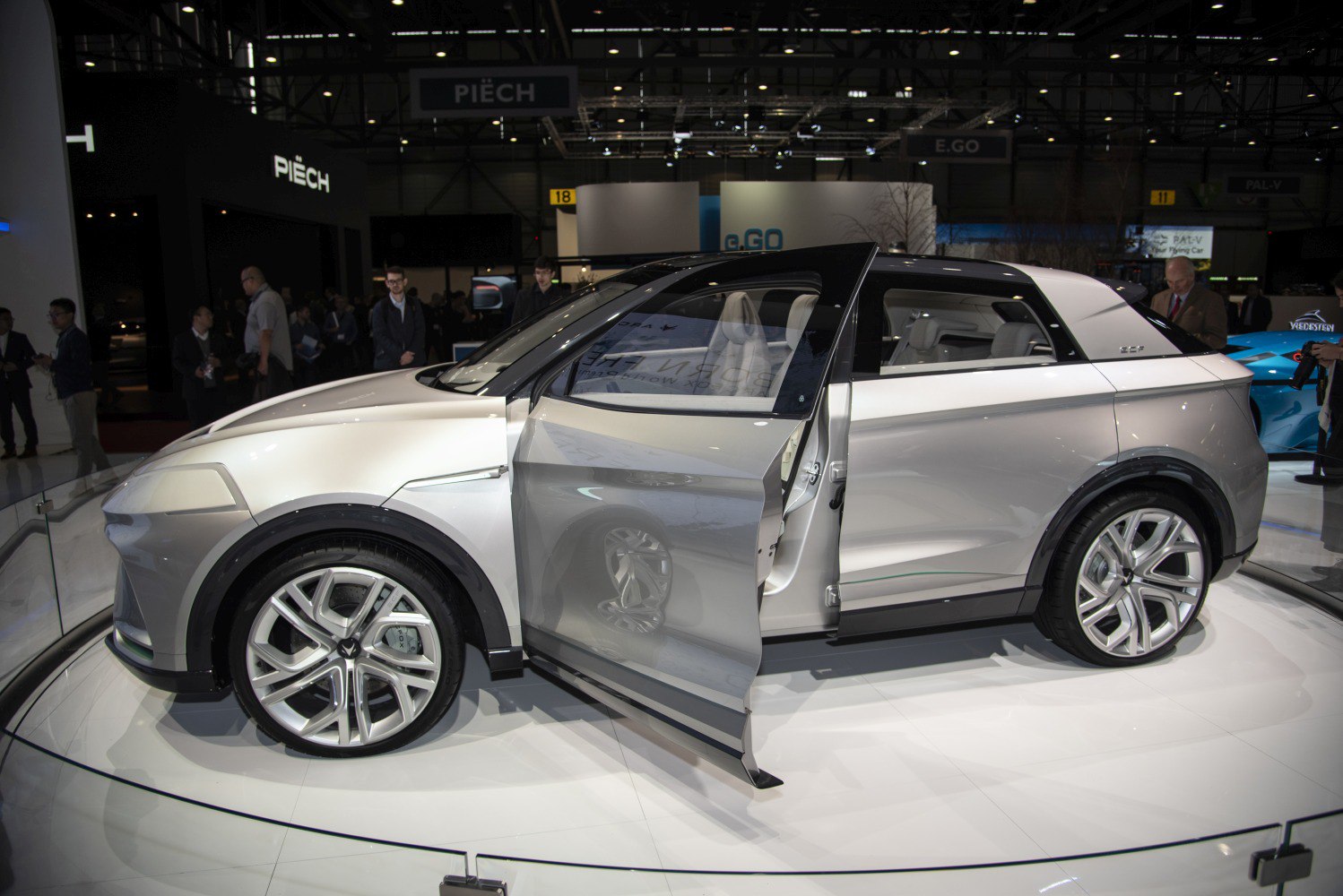Silver electric SUV with unique door design and large wheels at auto show
