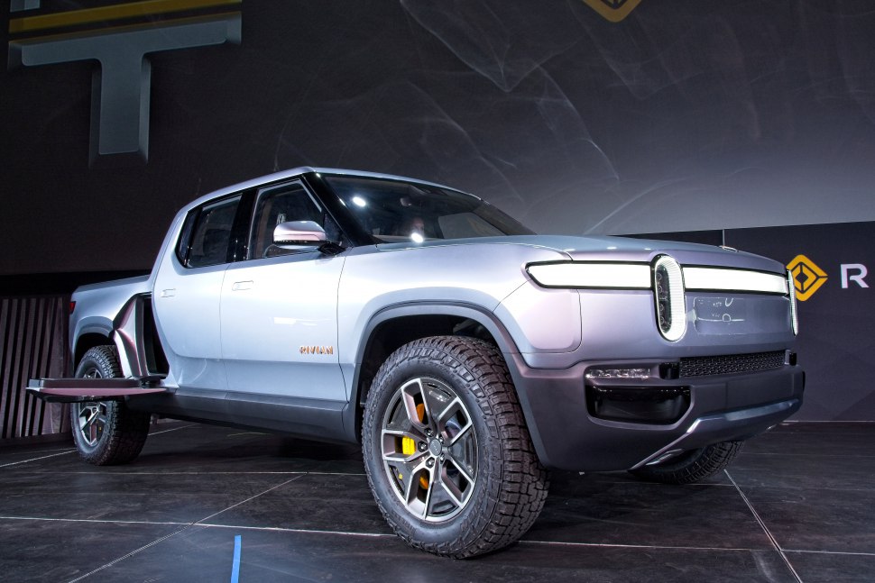 Electric pickup truck with distinctive LED headlights and open side storage compartment.