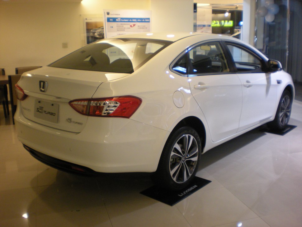Rear and side profile of a white modern sedan with alloy wheels and clear tail lights
