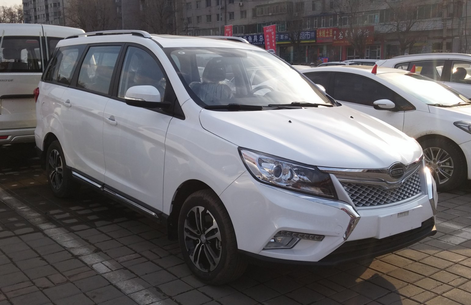 White MPV front side view with alloy wheels and roof rails