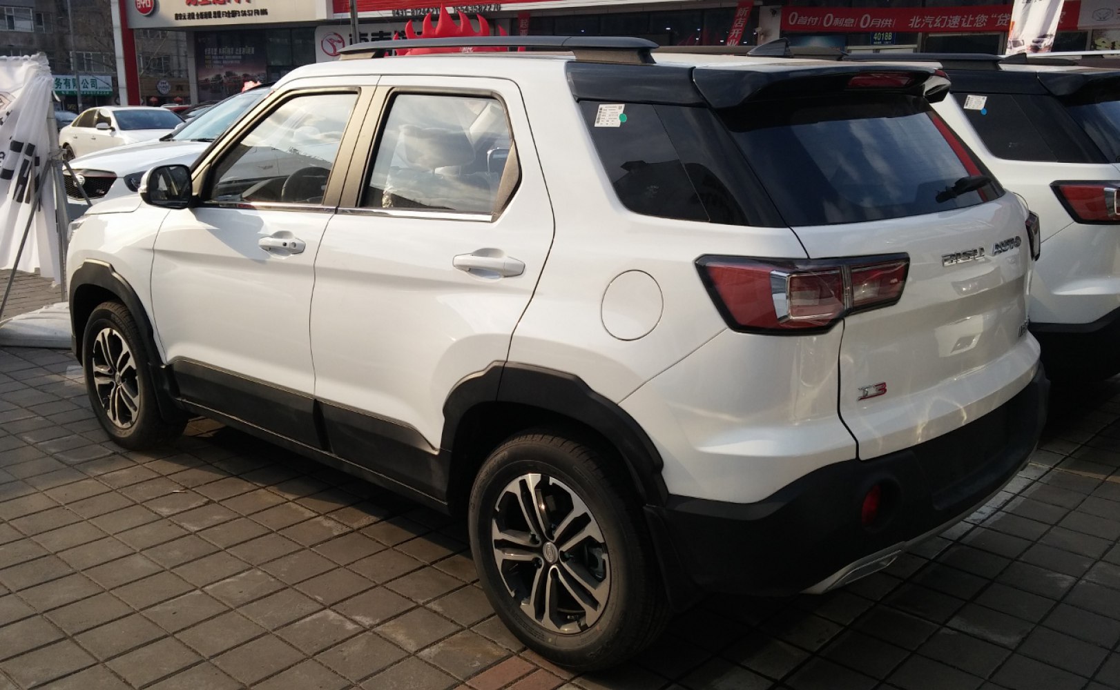 Rear side view of white SUV with alloy wheels and black protective cladding.