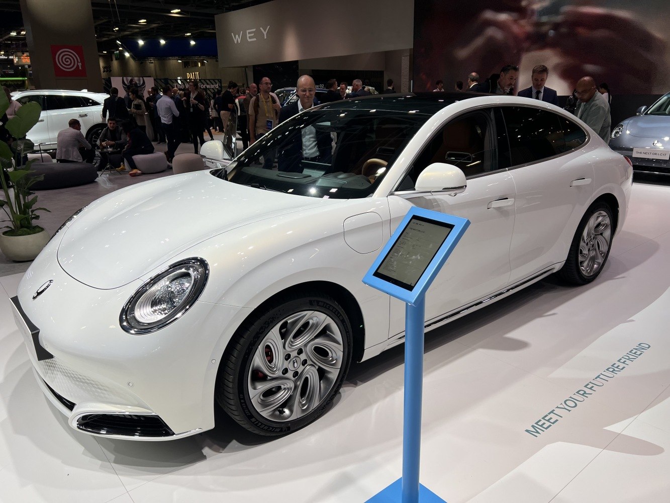 White electric sedan with oval headlights and aerodynamic body.