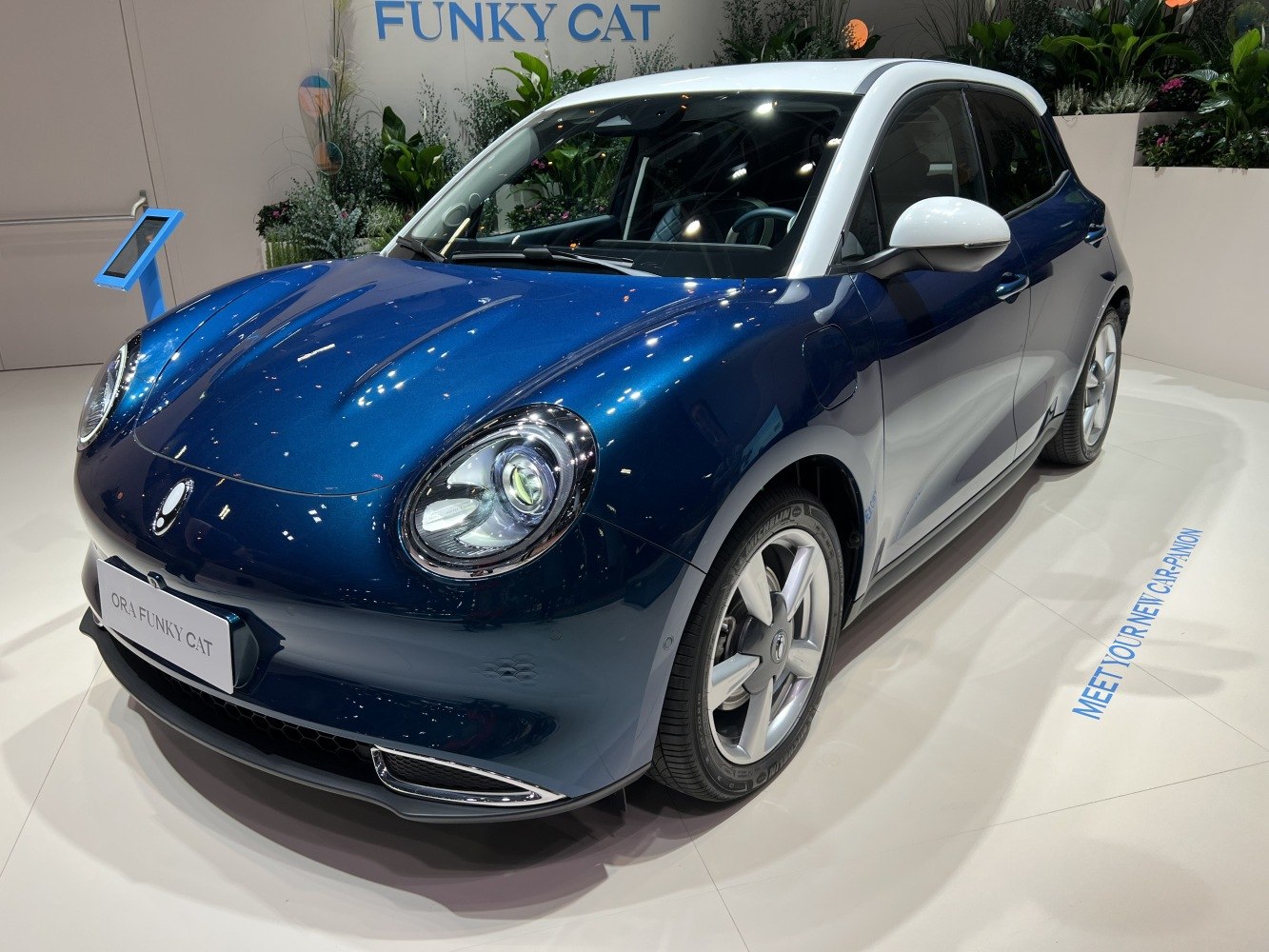 Compact electric vehicle with retro round headlights and curved body design.