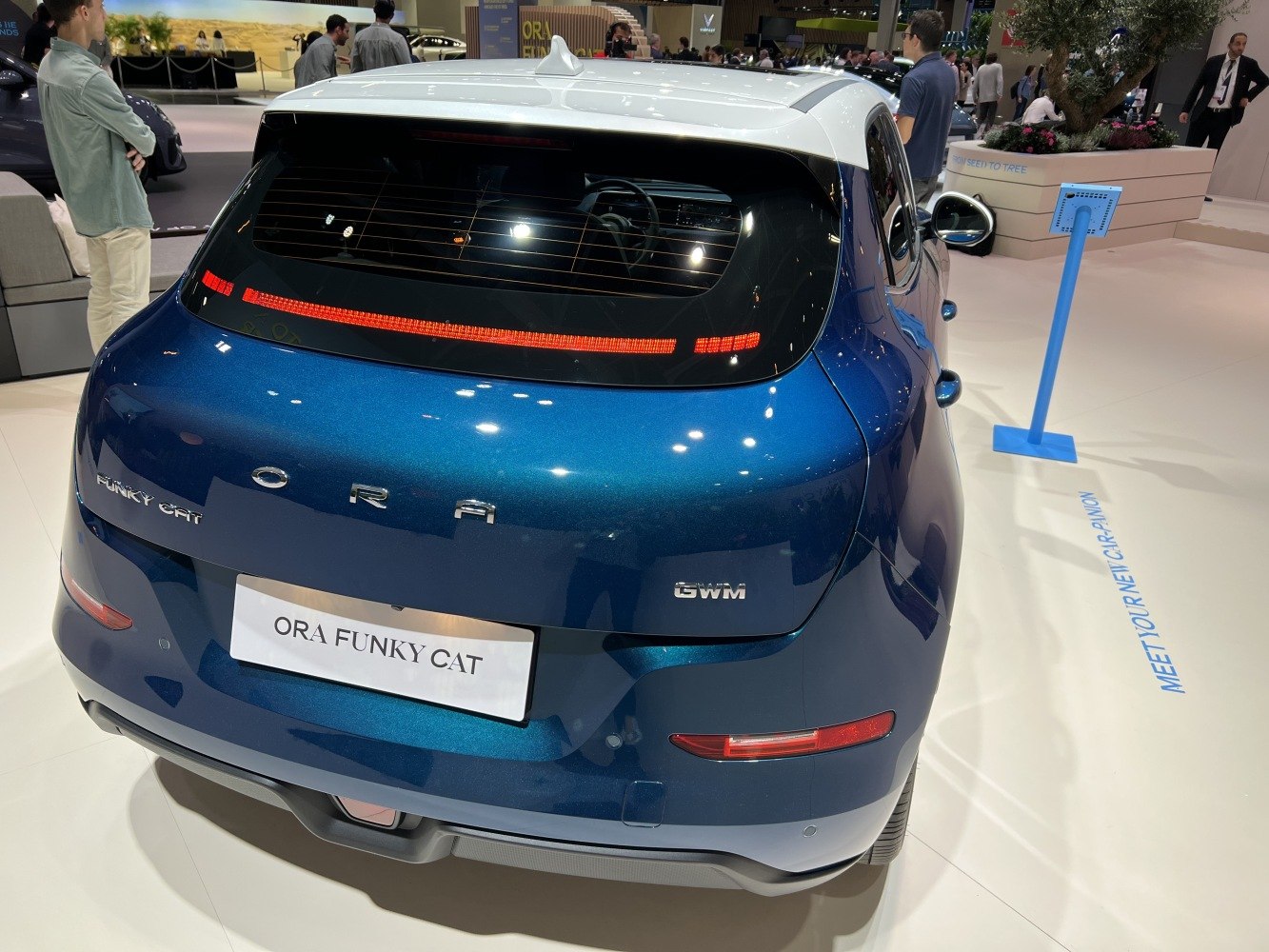 Rear view of blue electric hatchback with distinctive tail light and white roof