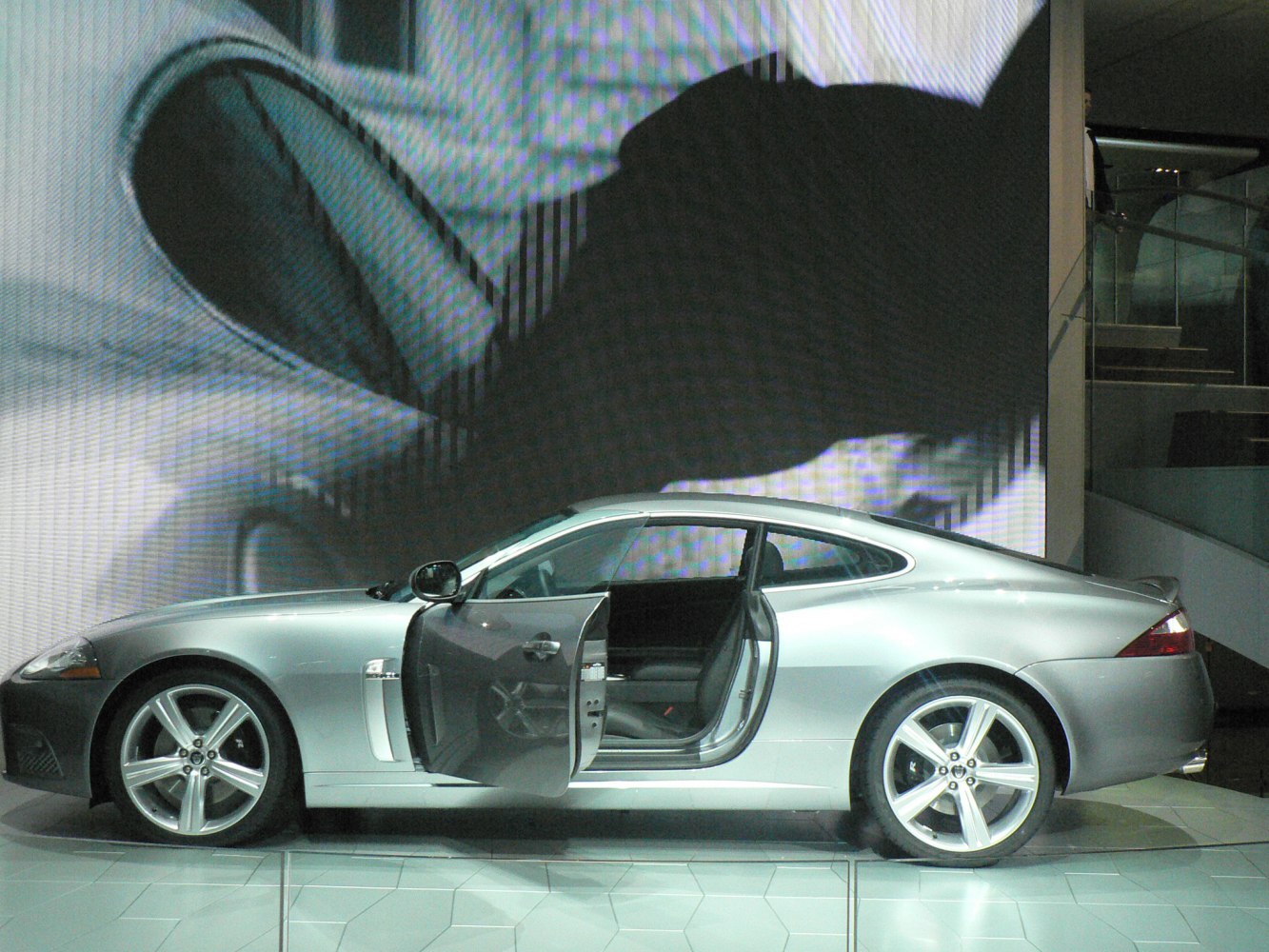 Silver coupe side profile with open driver's door and alloy wheels