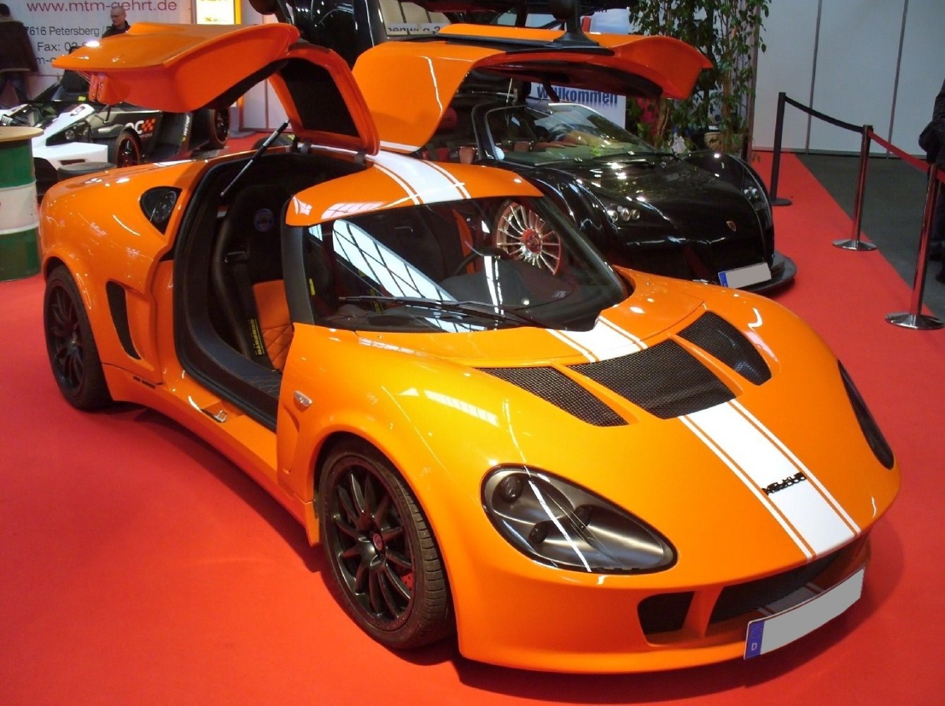 Orange sports car with gullwing doors and white racing stripes