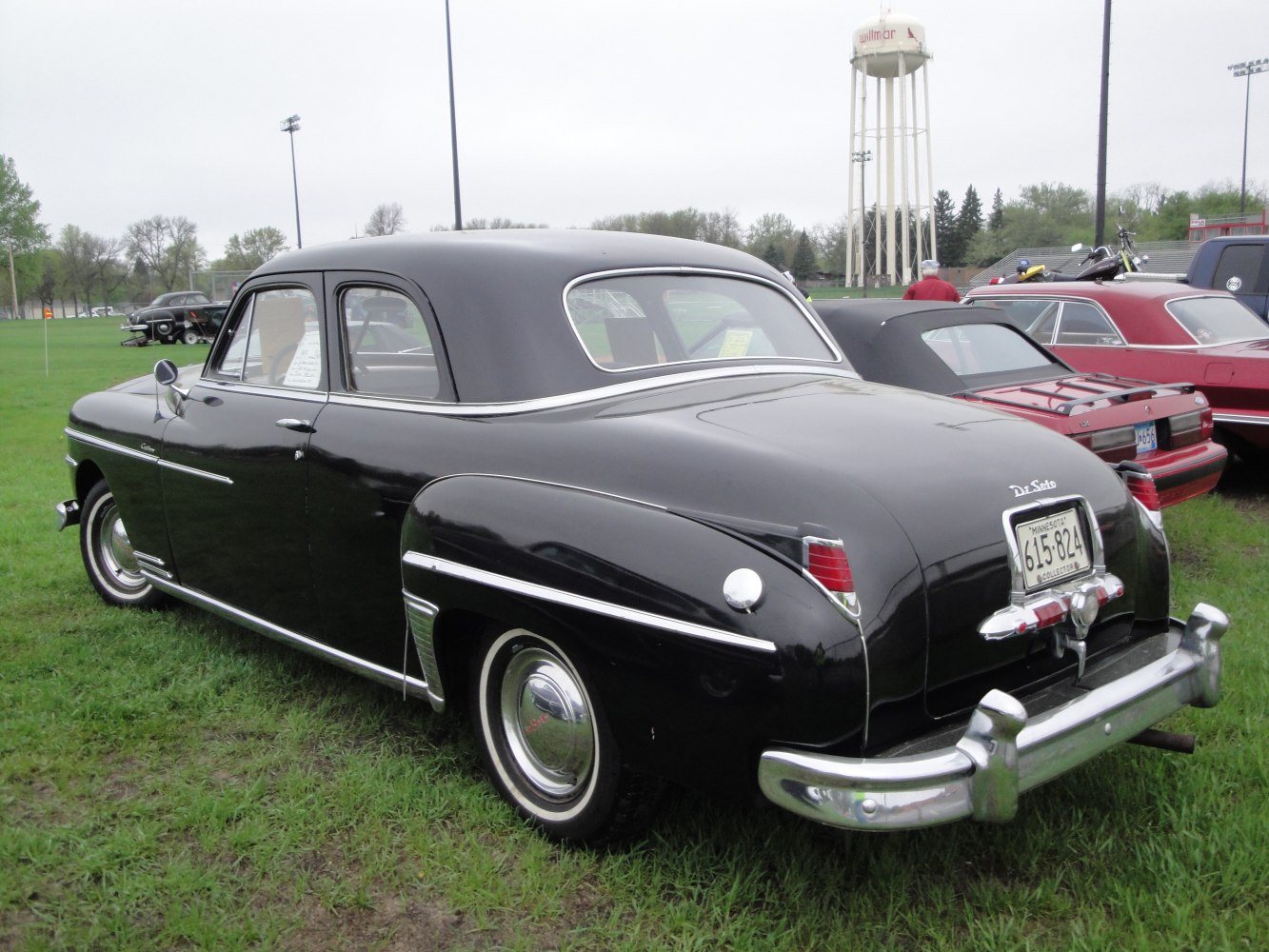 Black vintage coupe with chrome trim and whitewall tires, showing rear and side details
