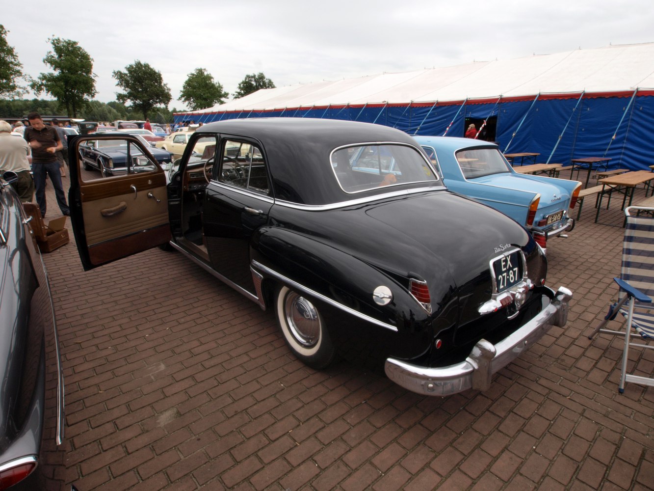 Black 4-door sedan rear with open door and whitewall tires
